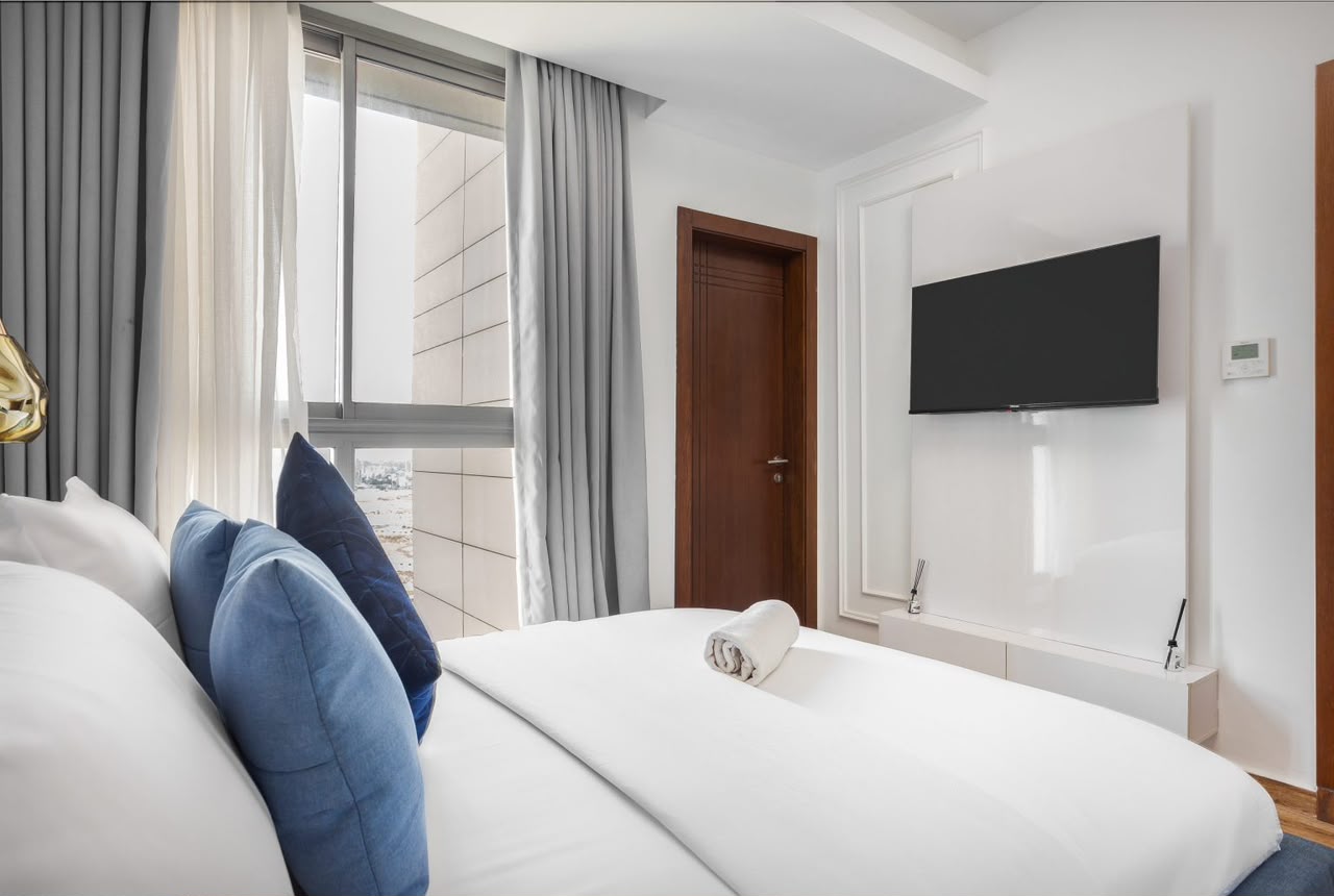 Eko Pearl bedroom with white bedding and wall-mounted TV